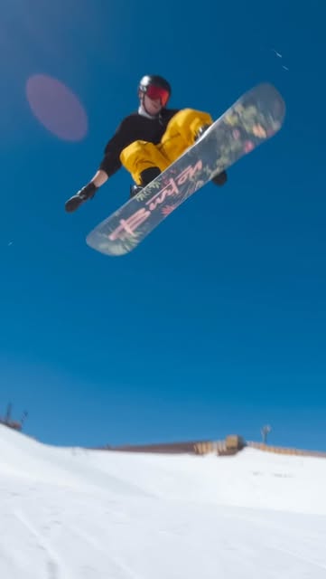 Álvaro salta con su tabla de snowboard sobre una pista nevada.
