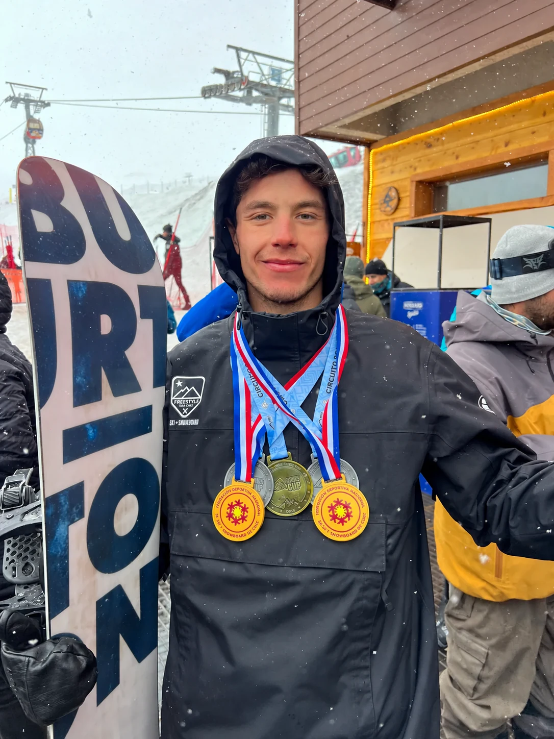 Álvaro Yáñez con su snowboard y medallas en la nieve.
